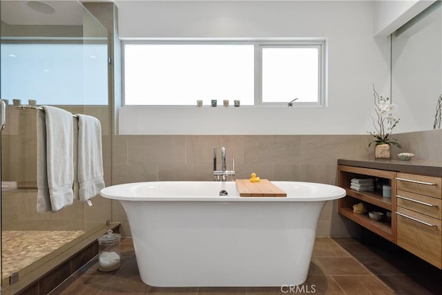 full bathroom with tile walls, a soaking tub, and a stall shower