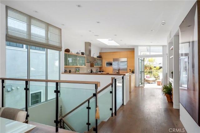 corridor featuring a skylight, an upstairs landing, and wood finished floors