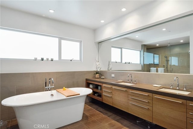 bathroom with double vanity, tile walls, a shower stall, and a sink