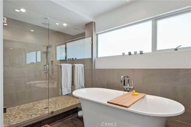 bathroom with a freestanding tub, tile walls, a stall shower, and recessed lighting