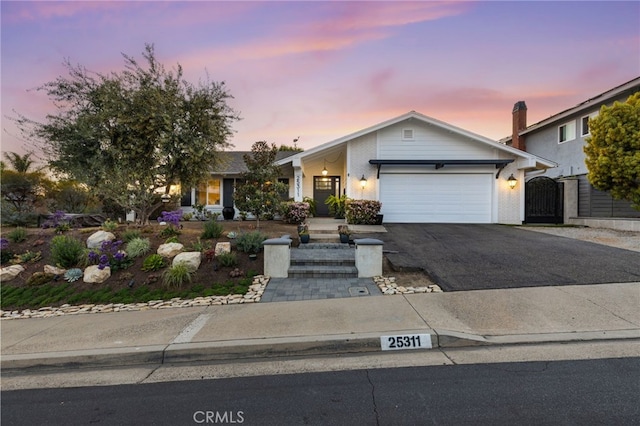 ranch-style home with an attached garage, driveway, and a gate