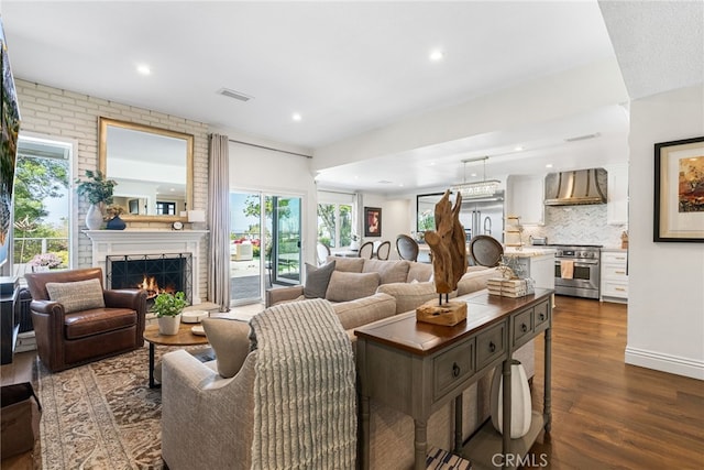 living room featuring recessed lighting, a brick fireplace, visible vents, and dark wood-style floors