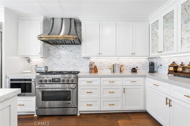 kitchen featuring white cabinets, stainless steel appliances, decorative backsplash, and wall chimney range hood