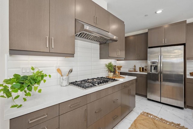 6784 Kenmar Way, San Diego, CA 92130 - kitchen with appliances with stainless steel finishes, under cabinet range hood, light marble finish floors, light countertops, and backsplash