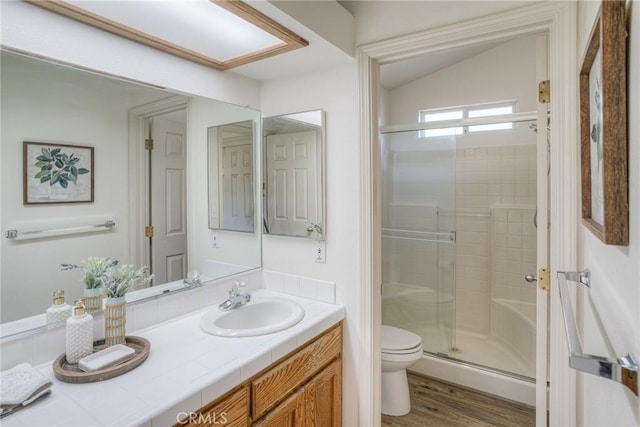 bathroom featuring wood finished floors, vanity, toilet, and a stall shower