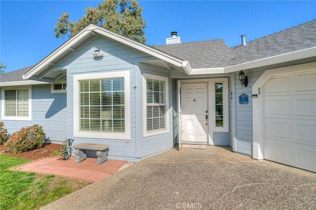 doorway to property featuring a garage, a shingled roof, and a chimney