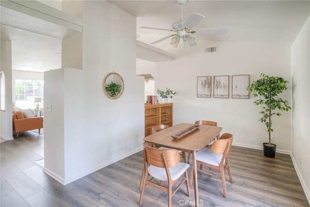 dining space featuring lofted ceiling, wood finished floors, visible vents, a ceiling fan, and baseboards