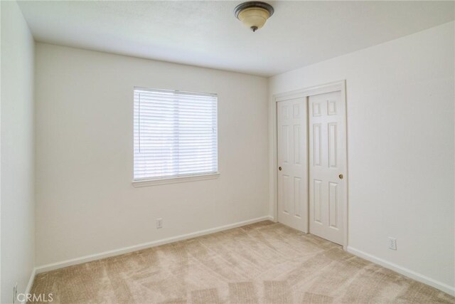 unfurnished bedroom featuring baseboards, carpet flooring, and a closet