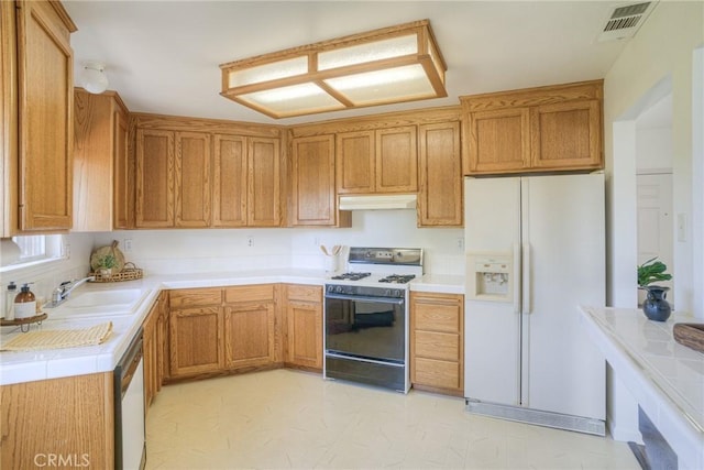kitchen with a sink, visible vents, white appliances, brown cabinetry, and under cabinet range hood