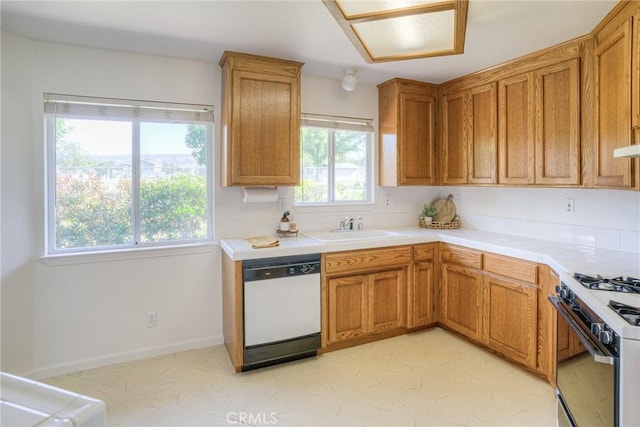 kitchen with brown cabinets, range with gas cooktop, white dishwasher, and a sink