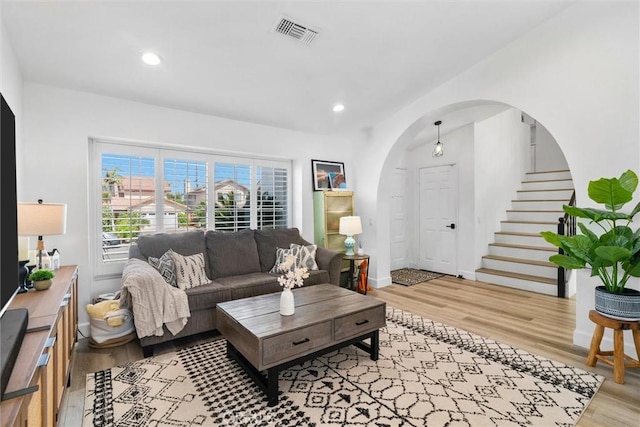 living area with recessed lighting, arched walkways, stairway, light wood-style floors, and visible vents
