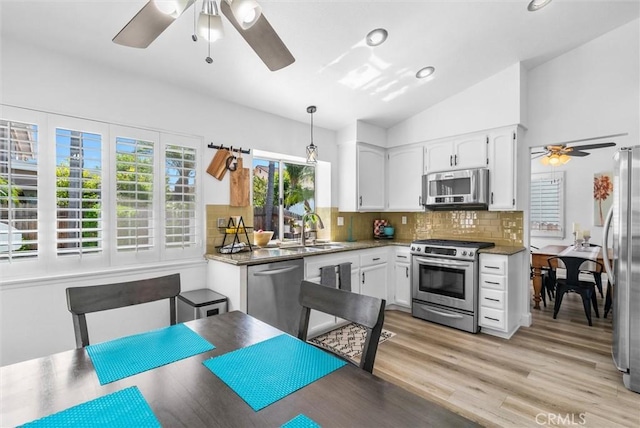 kitchen featuring appliances with stainless steel finishes, vaulted ceiling, white cabinets, a sink, and a ceiling fan