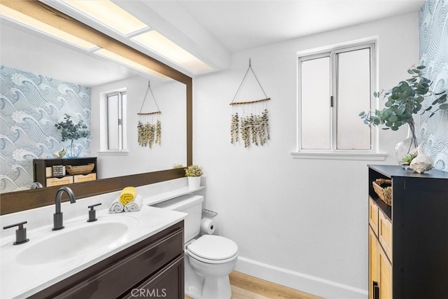 bathroom with baseboards, wood finished floors, toilet, and vanity