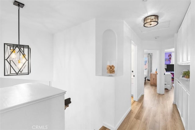 hall featuring attic access, baseboards, and light wood-type flooring