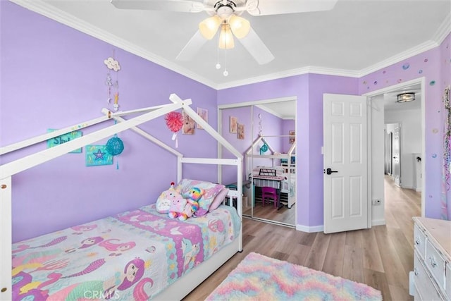 bedroom with wood finished floors, a closet, ornamental molding, baseboards, and a ceiling fan