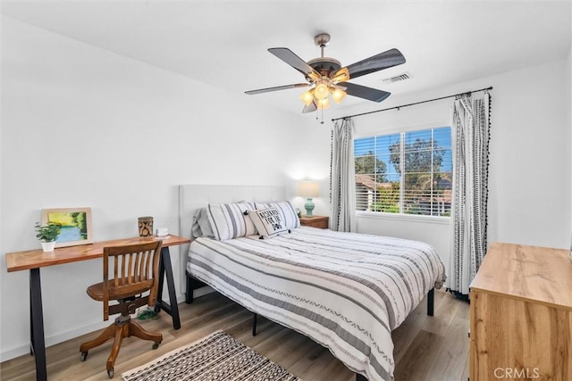 bedroom with baseboards, visible vents, wood finished floors, and ceiling fan