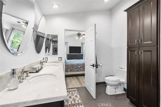 ensuite bathroom featuring toilet, a sink, ceiling fan, and connected bathroom