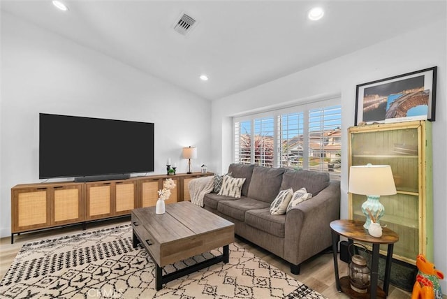 living room with recessed lighting, visible vents, vaulted ceiling, and light wood-type flooring