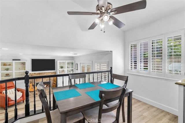 dining space with baseboards, a ceiling fan, lofted ceiling, and light wood-style flooring