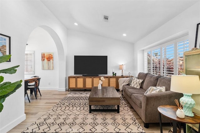 living area featuring lofted ceiling, visible vents, plenty of natural light, and light wood finished floors