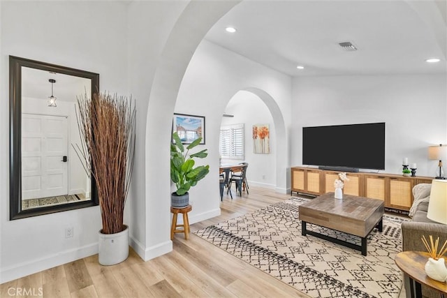 living area with recessed lighting, visible vents, baseboards, arched walkways, and wood finished floors