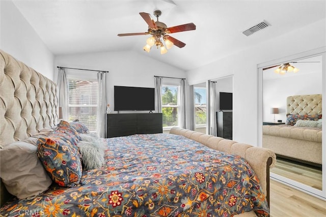 bedroom featuring lofted ceiling, wood finished floors, visible vents, and multiple windows