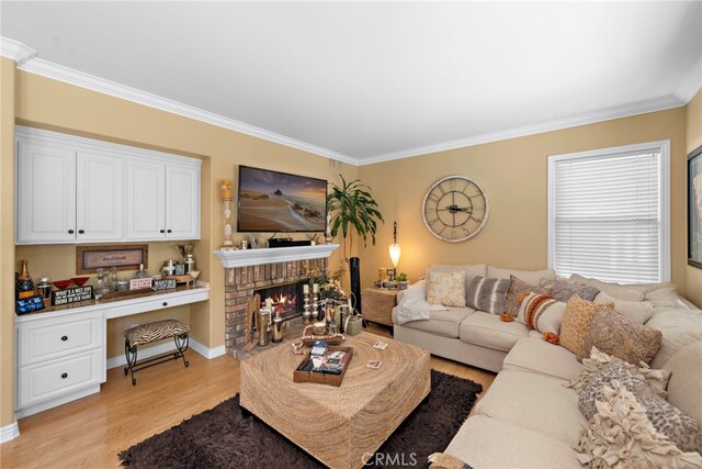 living room featuring built in study area, light wood finished floors, baseboards, ornamental molding, and a brick fireplace