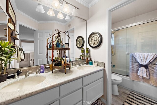 full bathroom featuring a sink, double vanity, toilet, crown molding, and enclosed tub / shower combo