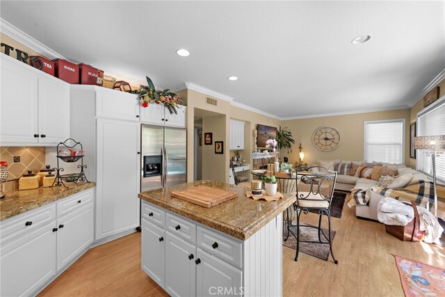 kitchen with white cabinets, light wood-style floors, a center island, and ornamental molding