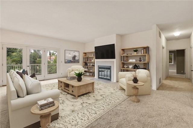 carpeted living room featuring a tile fireplace, visible vents, and french doors