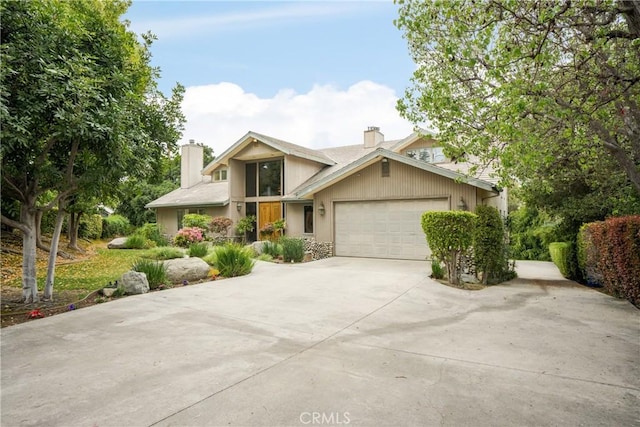 view of front of house featuring an attached garage, a chimney, and driveway