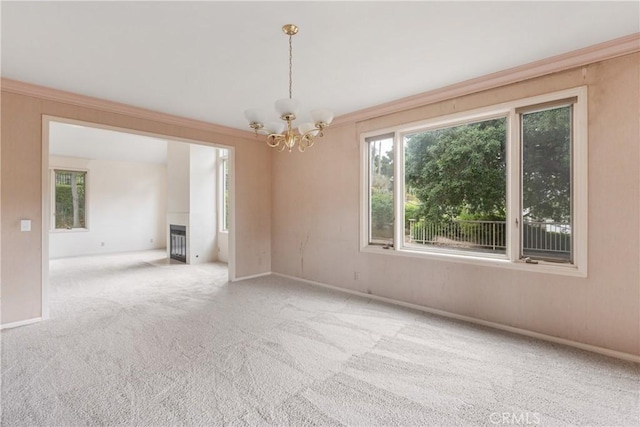 empty room with a tiled fireplace, carpet floors, a notable chandelier, and a wealth of natural light