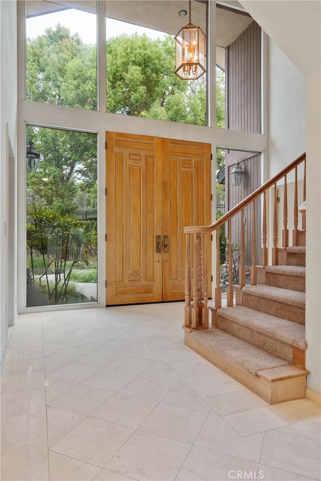 entrance foyer with stairs, a chandelier, and a towering ceiling