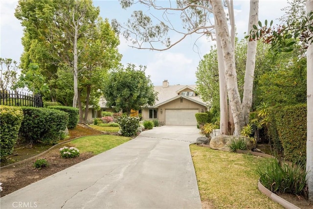 view of front of home featuring driveway, a front lawn, and fence