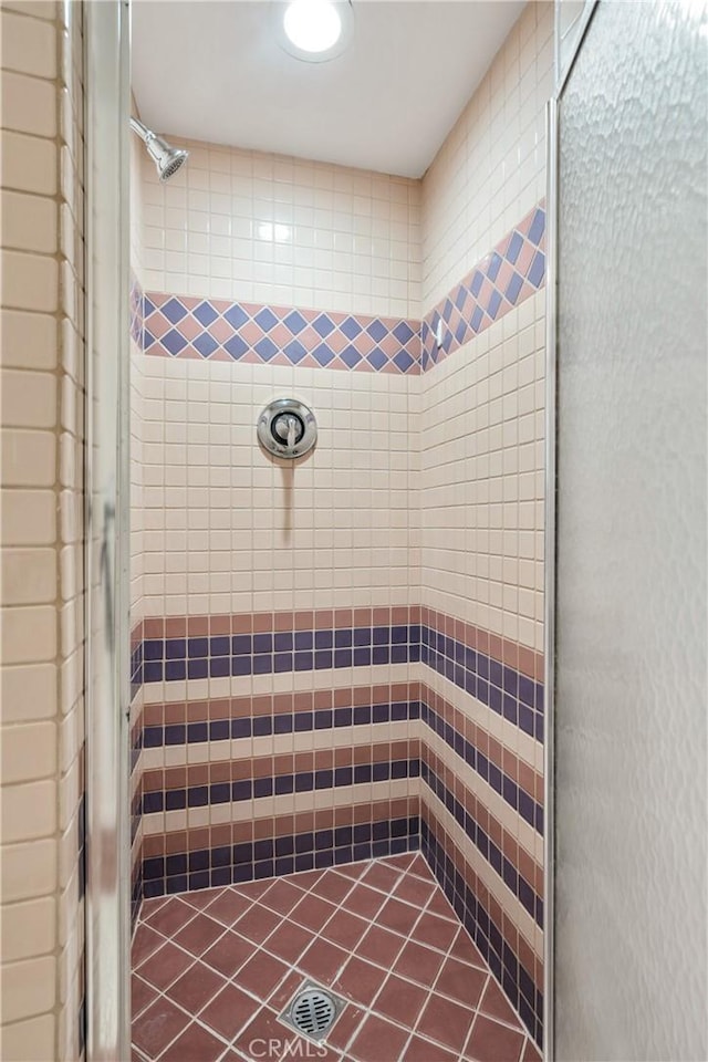 bathroom with a shower stall and tile patterned flooring