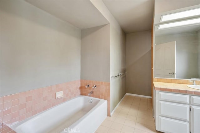 bathroom with tile patterned floors, a garden tub, vanity, and baseboards