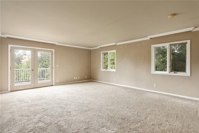 carpeted spare room with baseboards, ornamental molding, and french doors