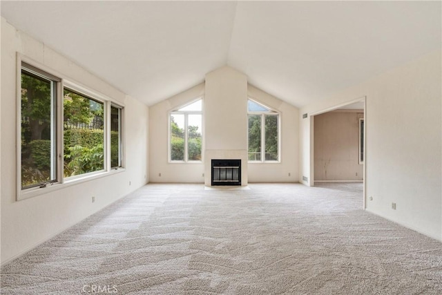 unfurnished living room featuring a fireplace with flush hearth, vaulted ceiling, and light colored carpet
