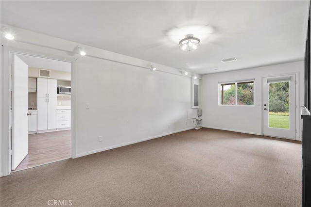 spare room with baseboards, visible vents, and carpet
