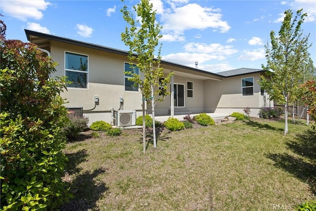 rear view of property with a patio area, ac unit, stucco siding, and a yard