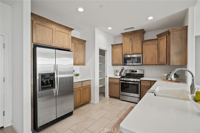 kitchen with a sink, tasteful backsplash, stainless steel appliances, and visible vents