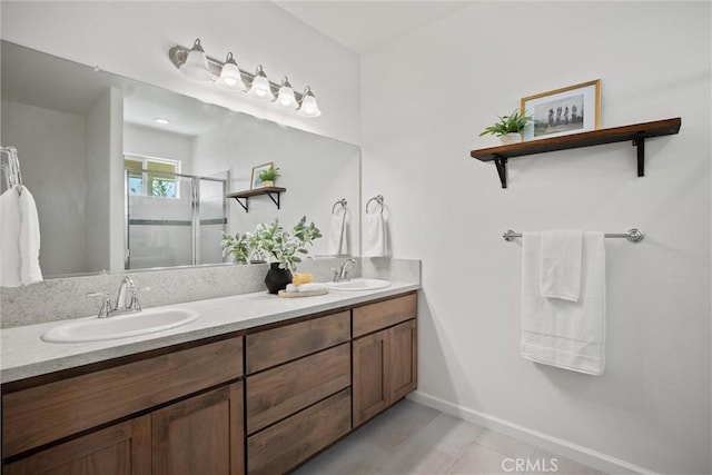 full bathroom featuring double vanity, a sink, baseboards, and a stall shower