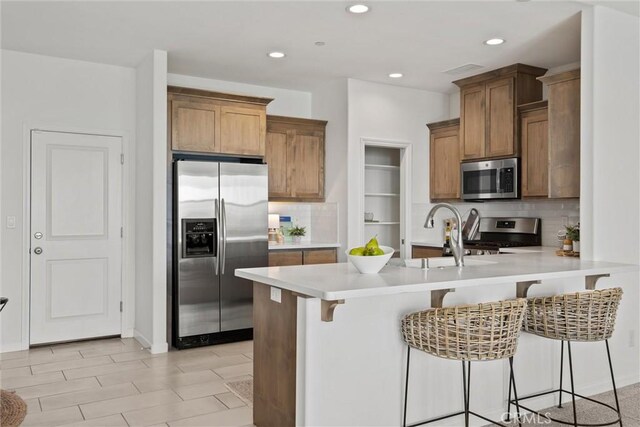 2991 Longwood Dr, Chico, CA 95928 - kitchen featuring decorative backsplash, a kitchen bar, appliances with stainless steel finishes, a sink, and a peninsula