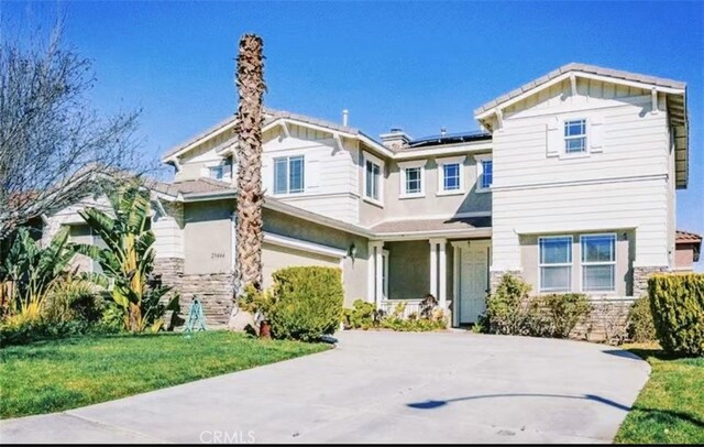 29444 Siderite Cir, Menifee, CA 92584 - craftsman-style house featuring a front lawn, stone siding, roof mounted solar panels, an attached garage, and driveway