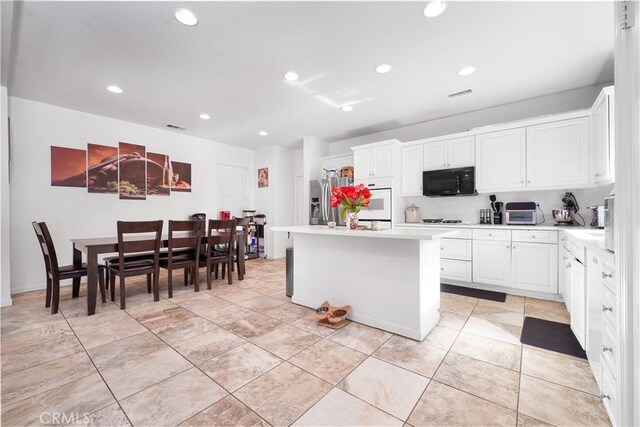 29444 Siderite Cir, Menifee, CA 92584 - kitchen featuring visible vents, black microwave, white oven, stainless steel refrigerator with ice dispenser, and light countertops