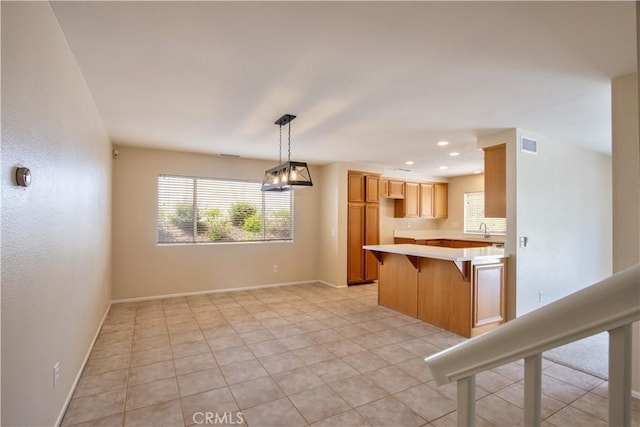32000 Corte Sagunto, Temecula, CA 92592 - kitchen featuring a sink, light countertops, a kitchen breakfast bar, decorative light fixtures, and visible vents
