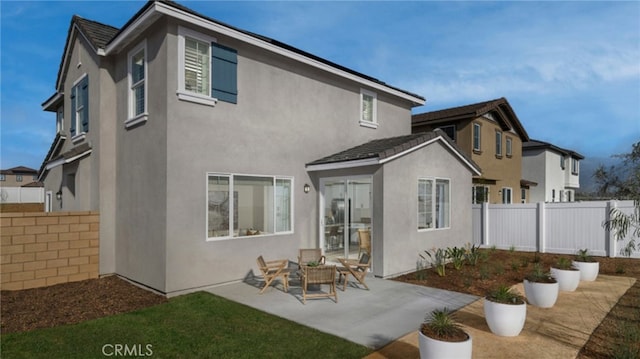 rear view of property with a patio area, stucco siding, and fence