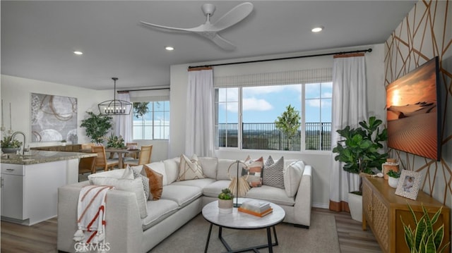 living room with ceiling fan with notable chandelier, wood finished floors, and recessed lighting