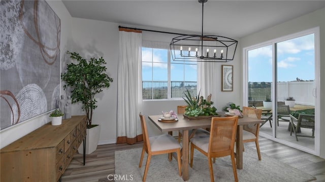 dining area featuring light wood-style floors, a wealth of natural light, baseboards, and a notable chandelier