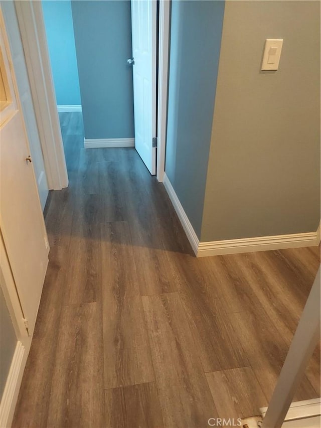 corridor with wood finished floors and baseboards